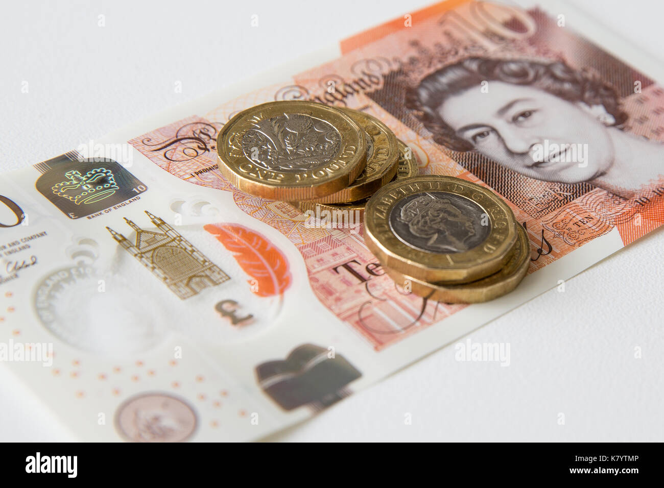 Image of the new, plastic, ten pound, sterling, note with five one pound sterling coins on top of it. Stock Photo