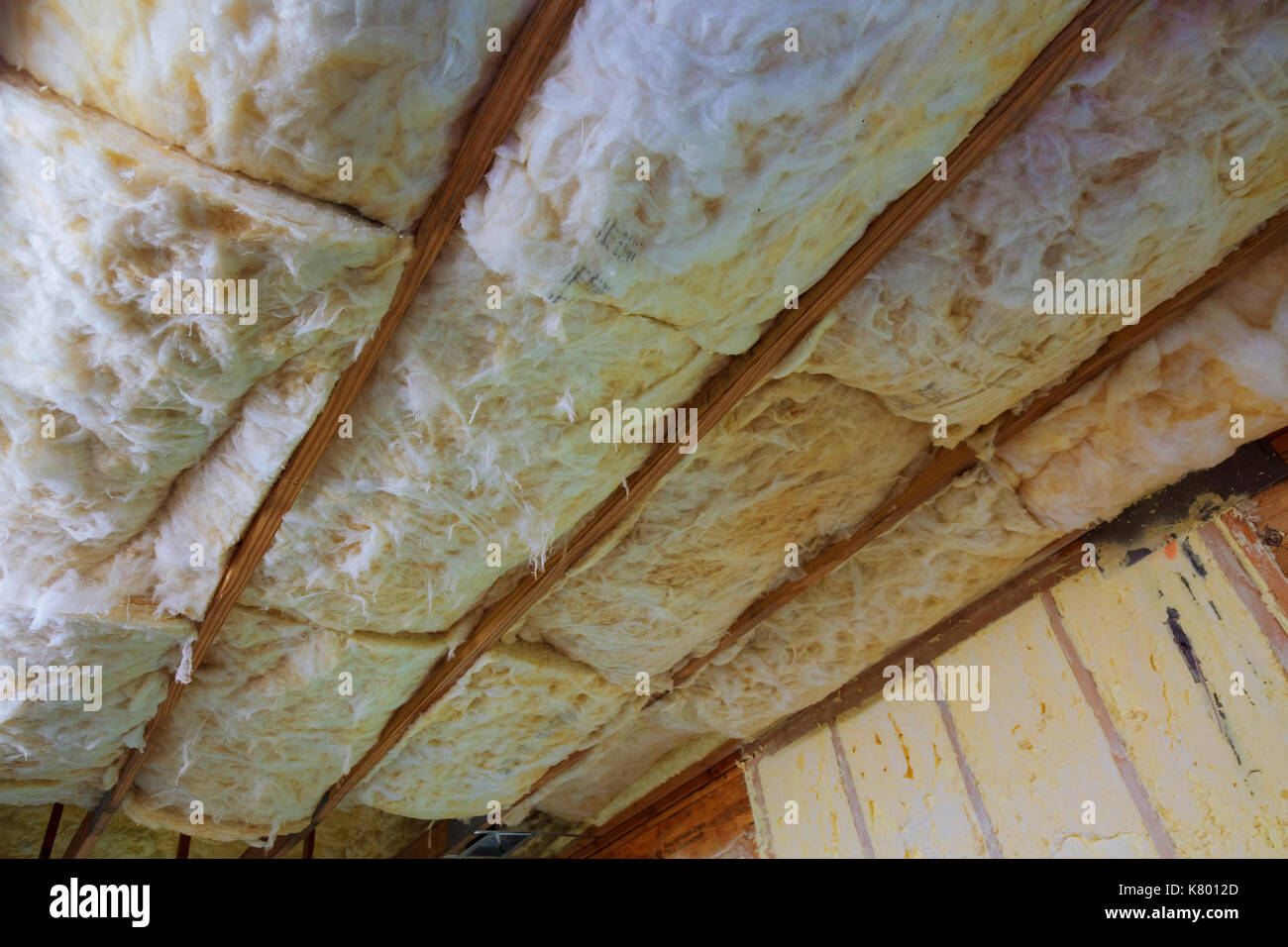 Closeup of strips of pink fiberglass insulation in a wall of a new