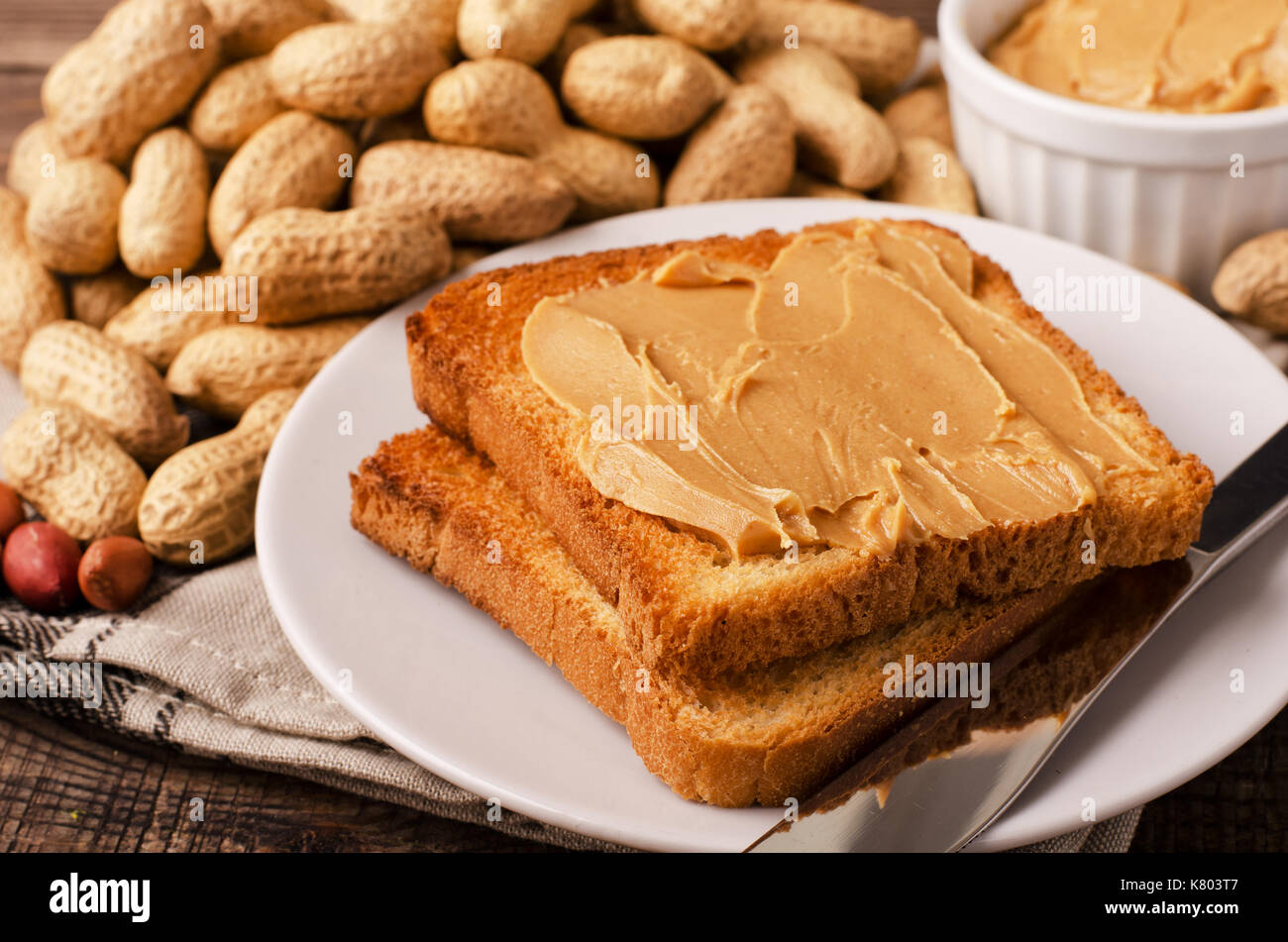 Peanut butter sandwich on plate with inshell peanuts, breakfast on the
