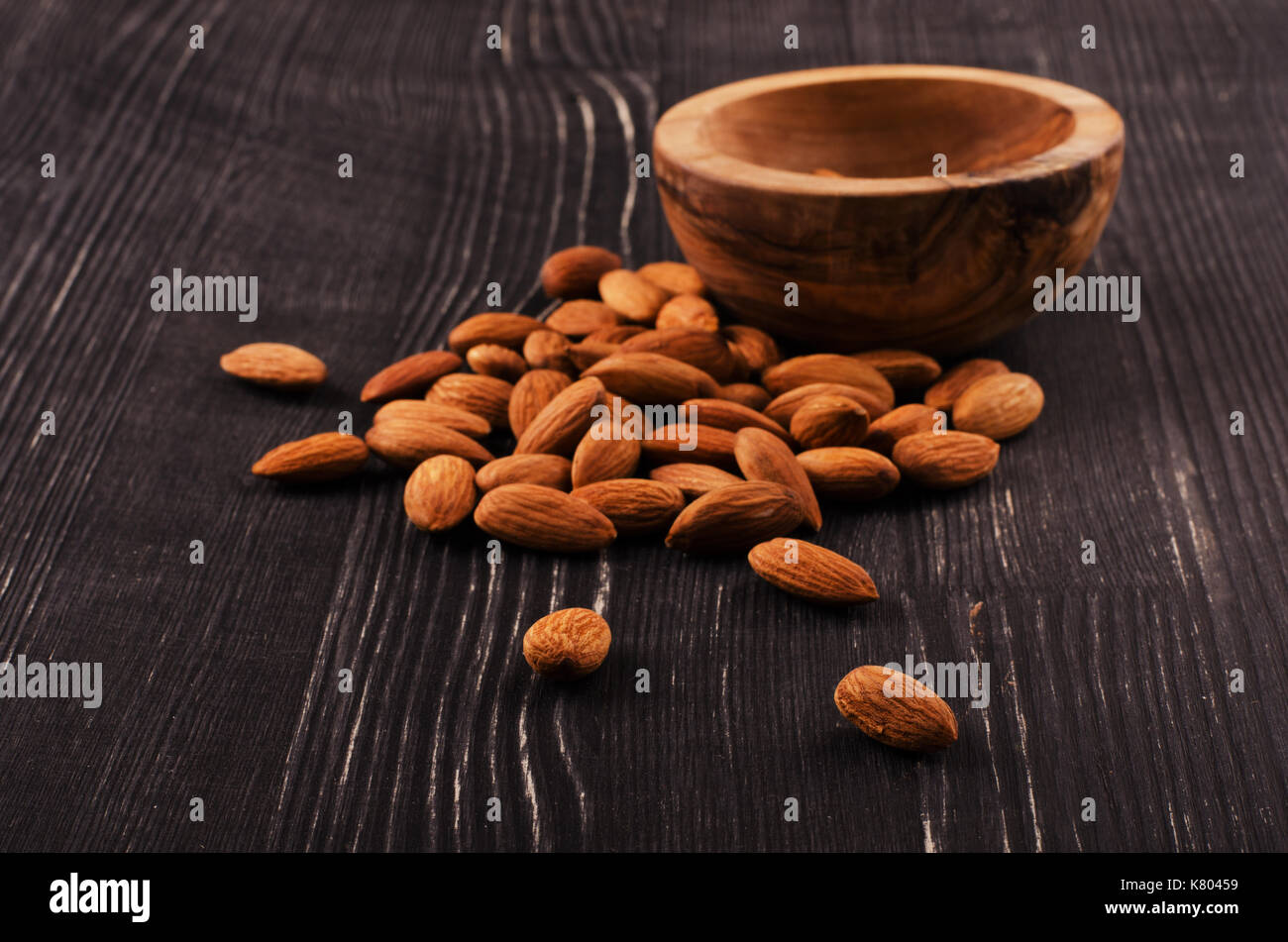 Almonds in brown bowl on wooden background Stock Photo