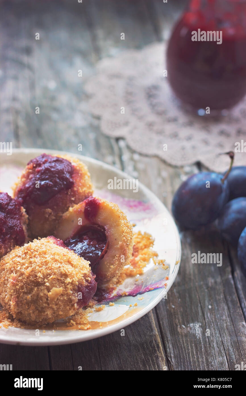 Plum dumplings, plums and plum sauce on wooden background Stock Photo