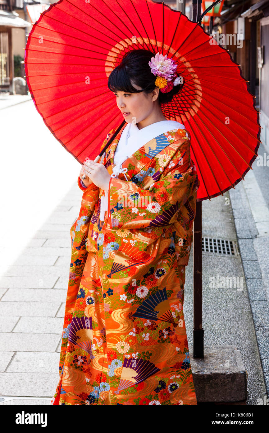 Japan, Kanazawa, Higashi Chaya. Side-view Japanese young women standing in  kimono and holding big red parsole. Flowers in her hair Stock Photo - Alamy