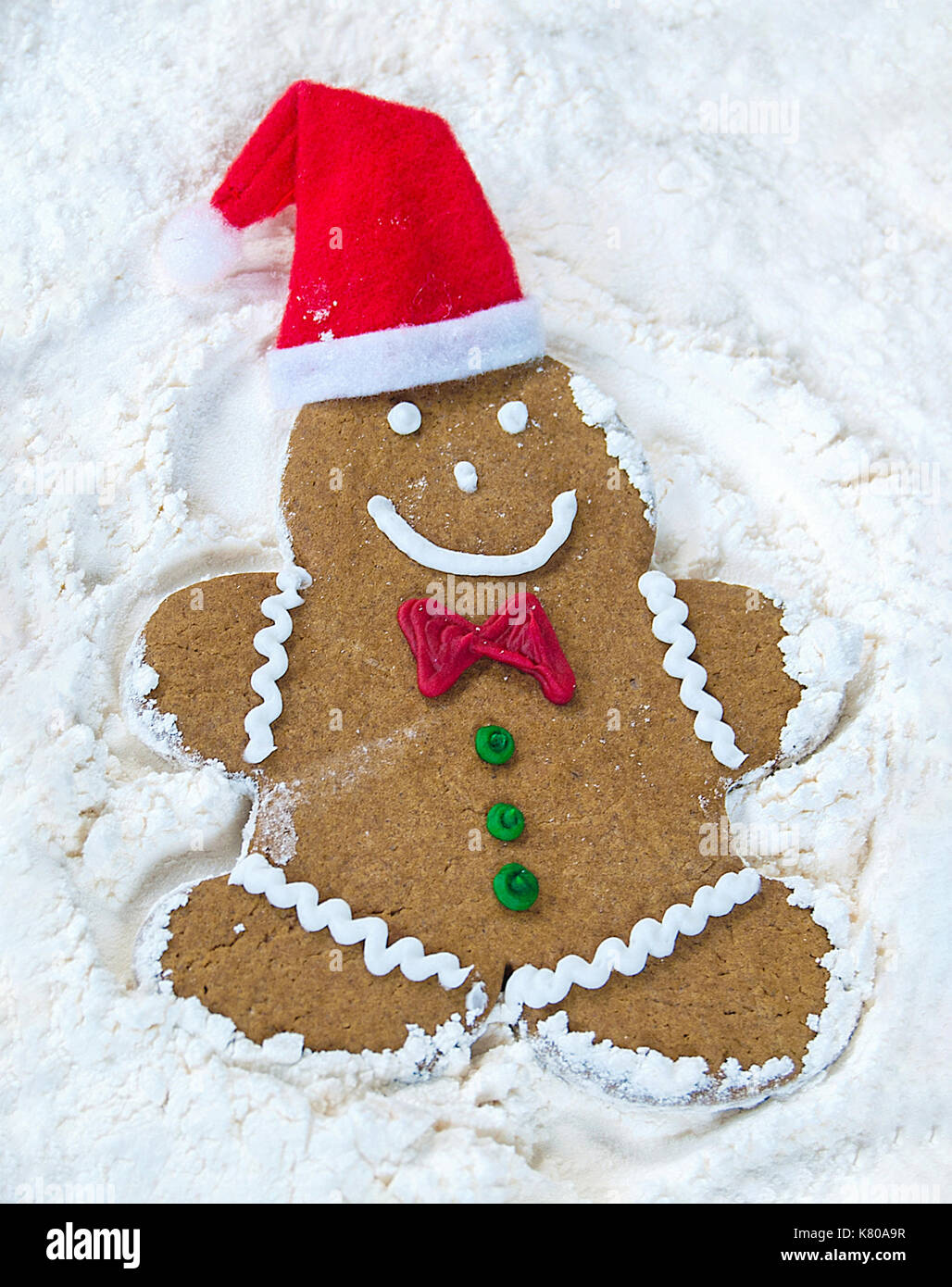 Christmas gingerbread man with hat making snow angel in white flour Stock Photo