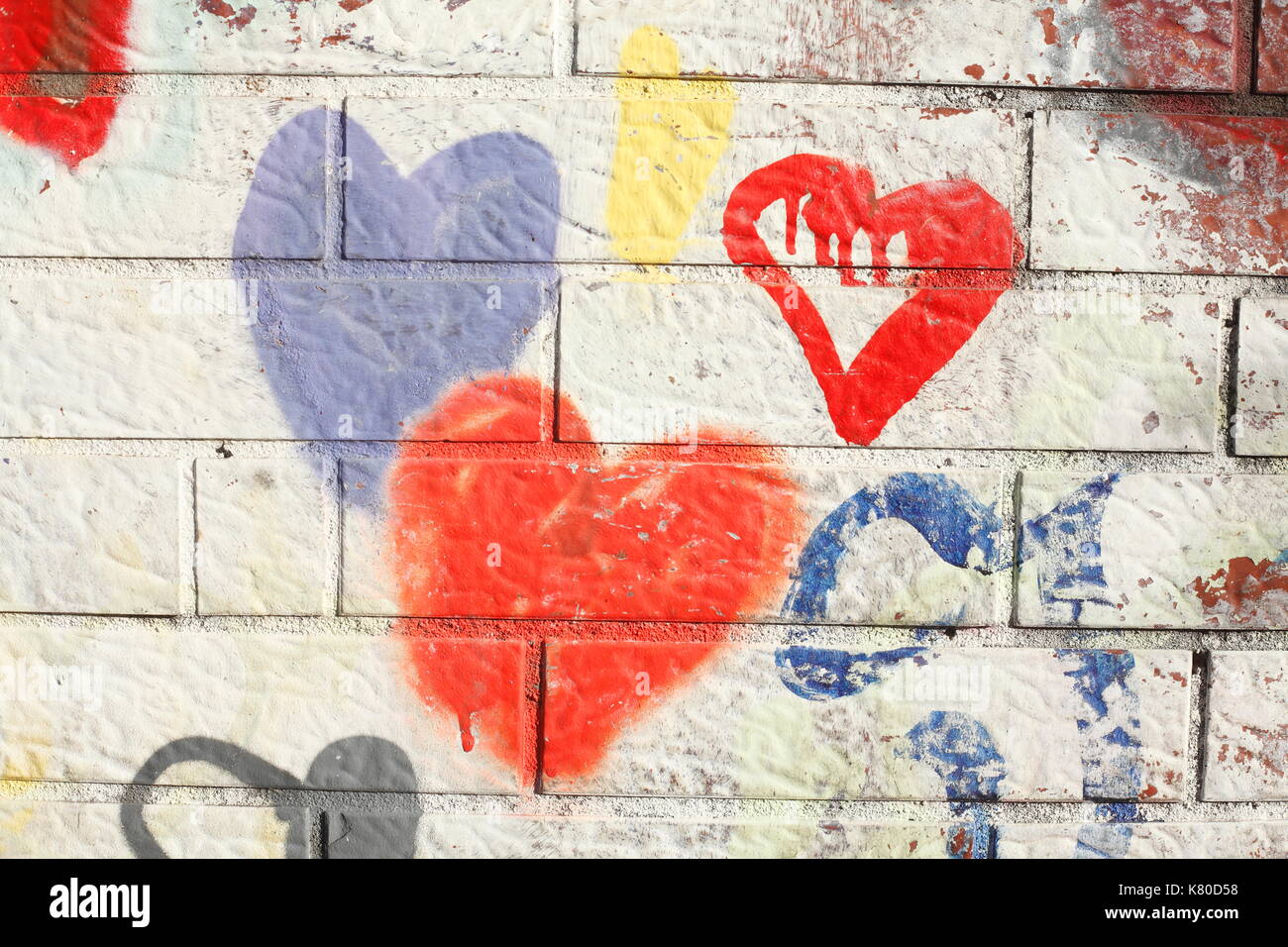 colorful hearts painted on a white brick wall Stock Photo