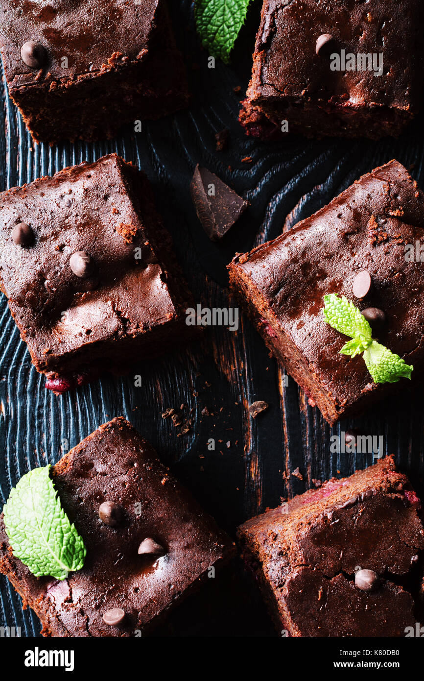 Dark chocolate brownies decorated with mint leaf on dark background. Top view, vertical