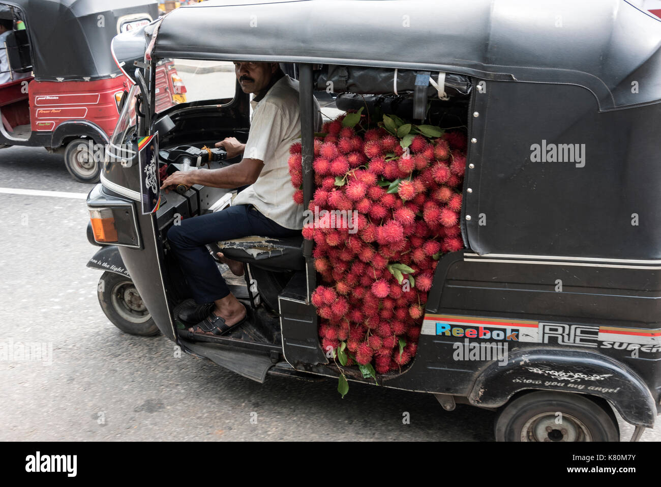 A  tuk-tuk carrying a load of  Rambutan, a Malaysian fruit to market in Colombo in Sri Lanka. Stock Photo