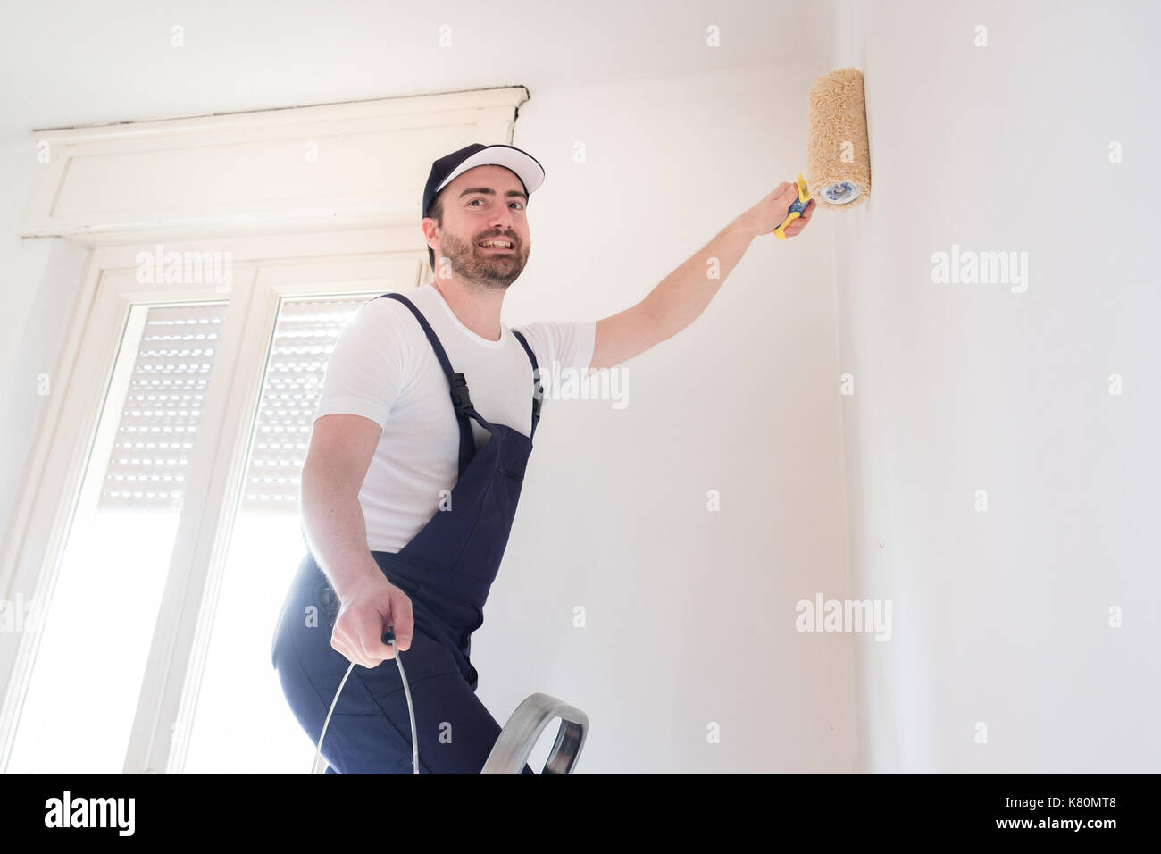 Professional painter worker is painting a wall Stock Photo