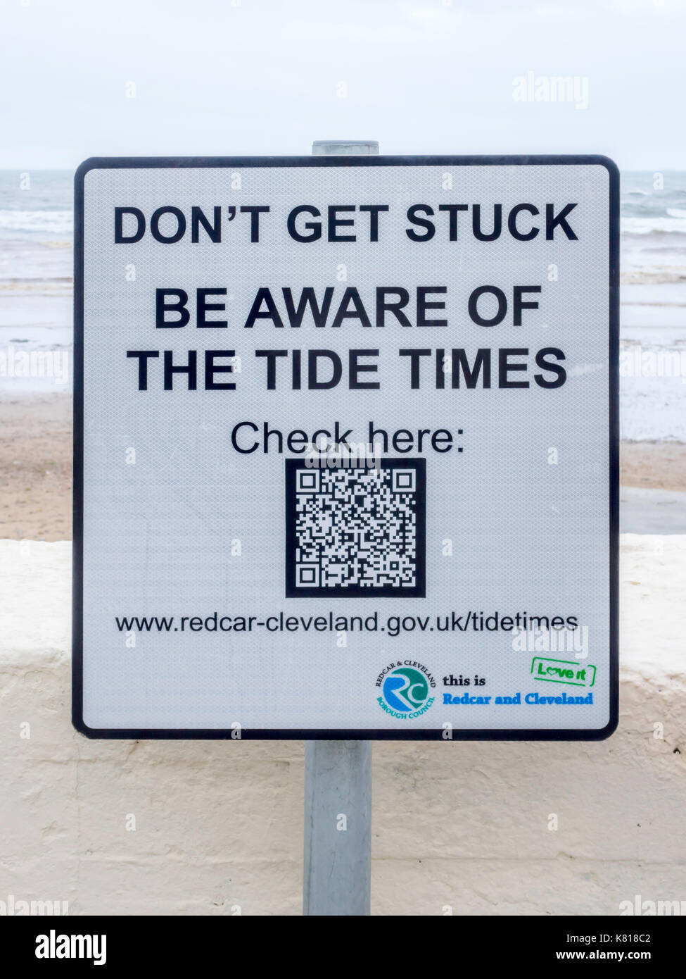 Notice by Saltburn Beach at a notorious danger spot warning against being cut off by the tide with a QR code to provide a Tide Table on a smart phone Stock Photo