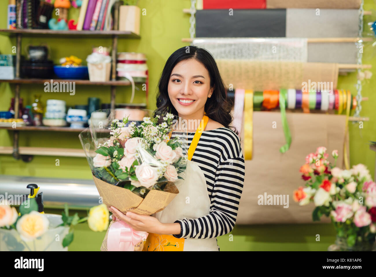 Beautiful asian female florist holding bouquet of flowers Stock Photo