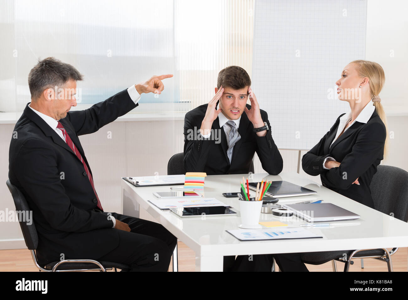 Mature Businessman Arguing With His Two Co-workers In Office Stock Photo