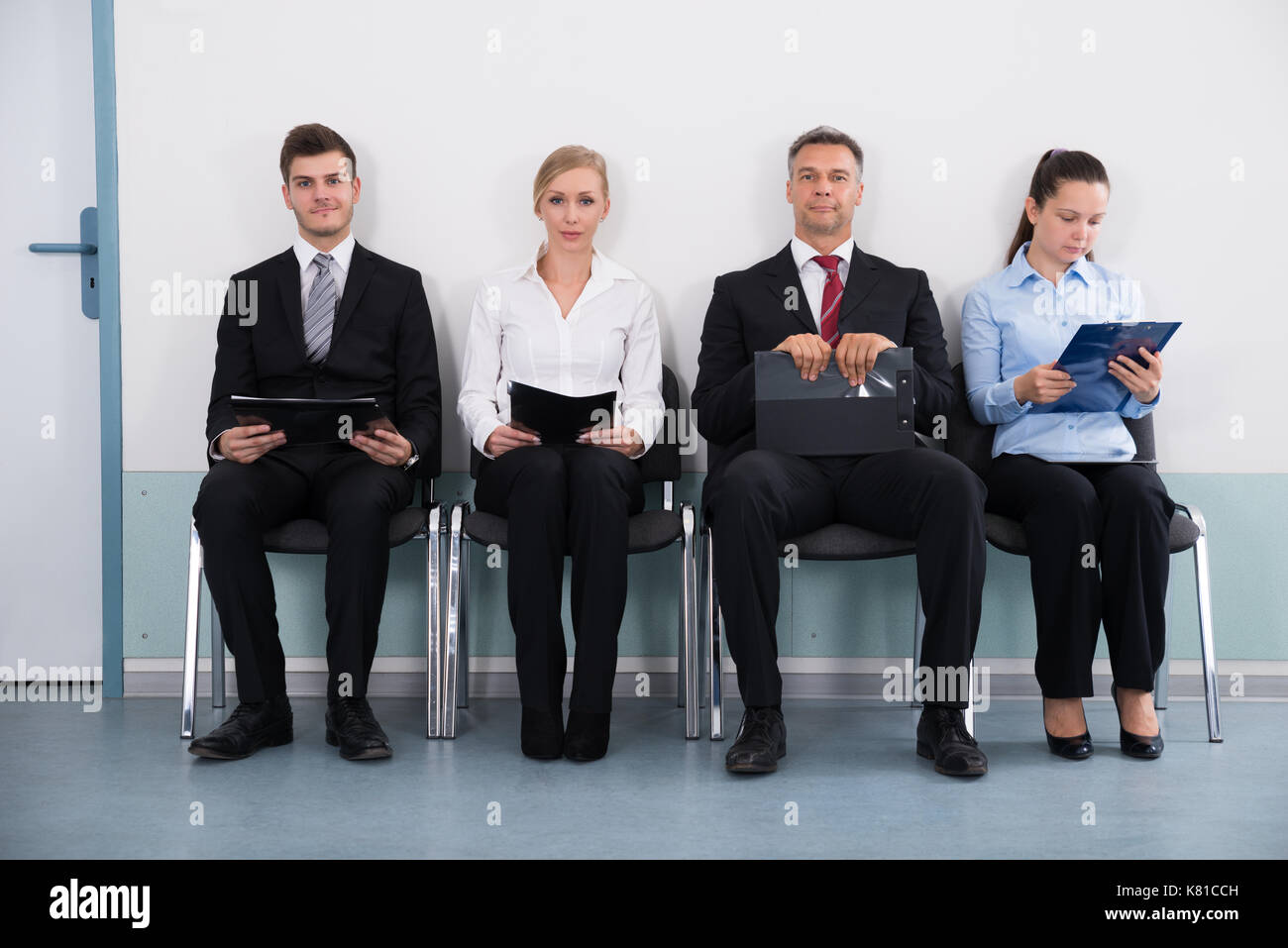 Group Of Businesspeople With Files Sitting On Chair For Giving Interview Stock Photo