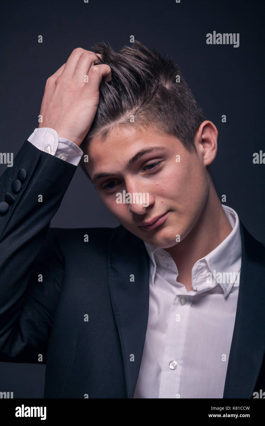 one young teenage boy, black background, studio, head face closeup, looking down Stock Photo