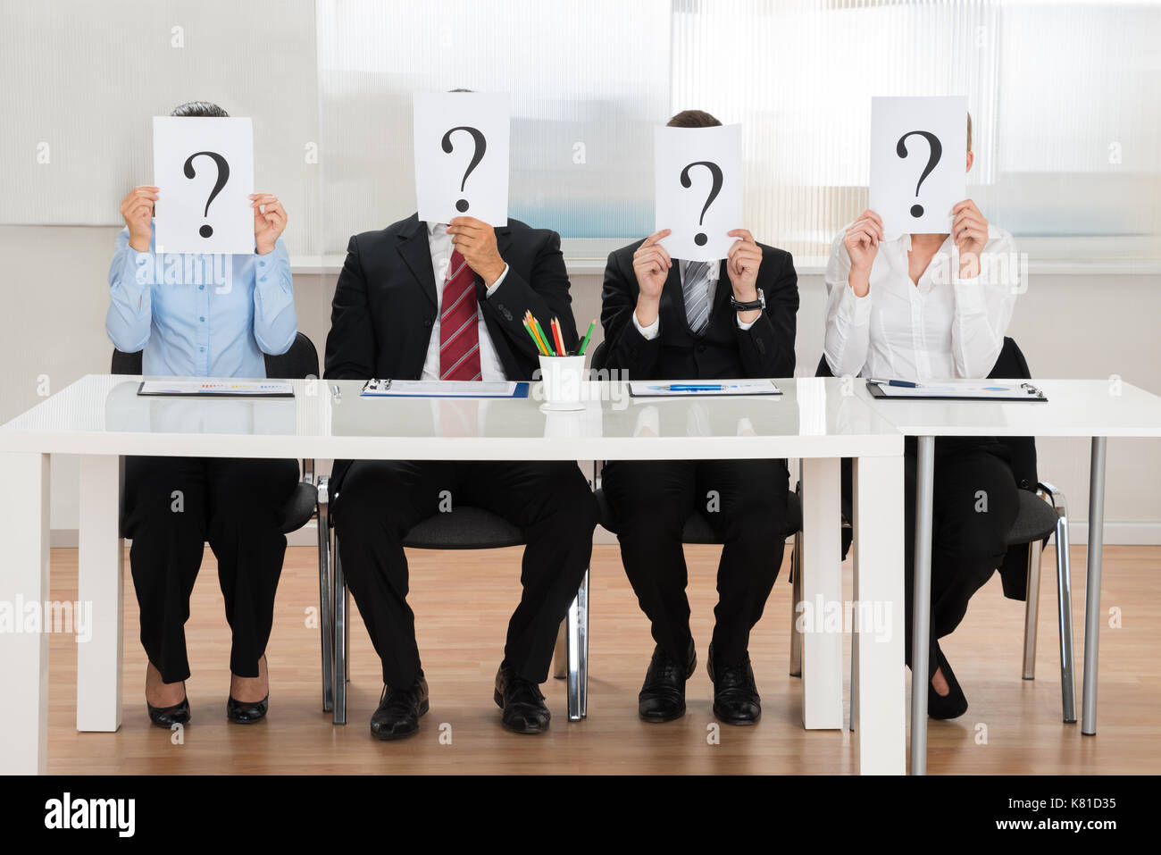 Businesspeople Team Hiding Face With Question Mark Sign At Desk Stock Photo