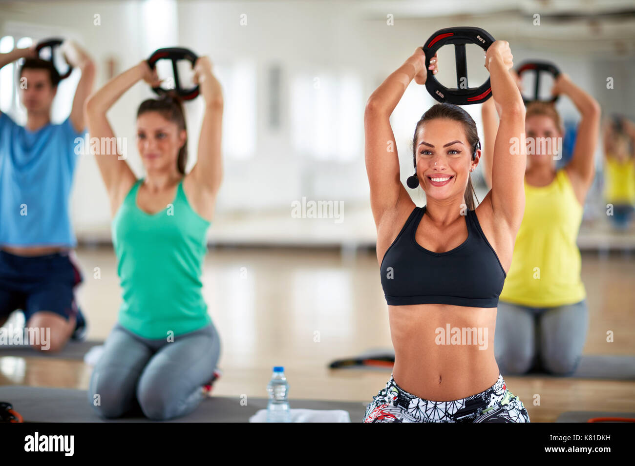 Female fitness instructor use weights for strengthening arms inside