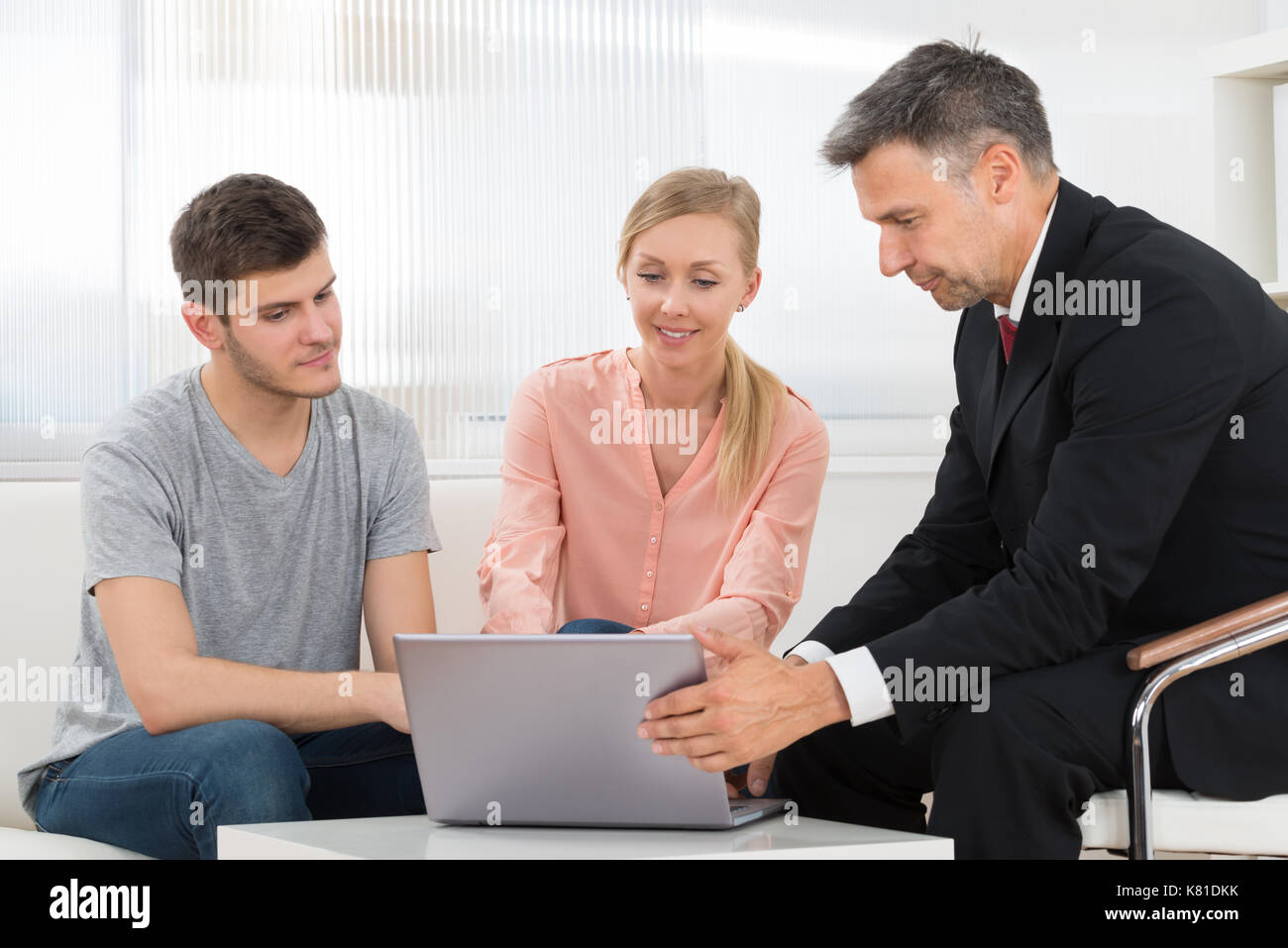 Financial Consultant Explaining Investment Plan To Young Couple Stock Photo