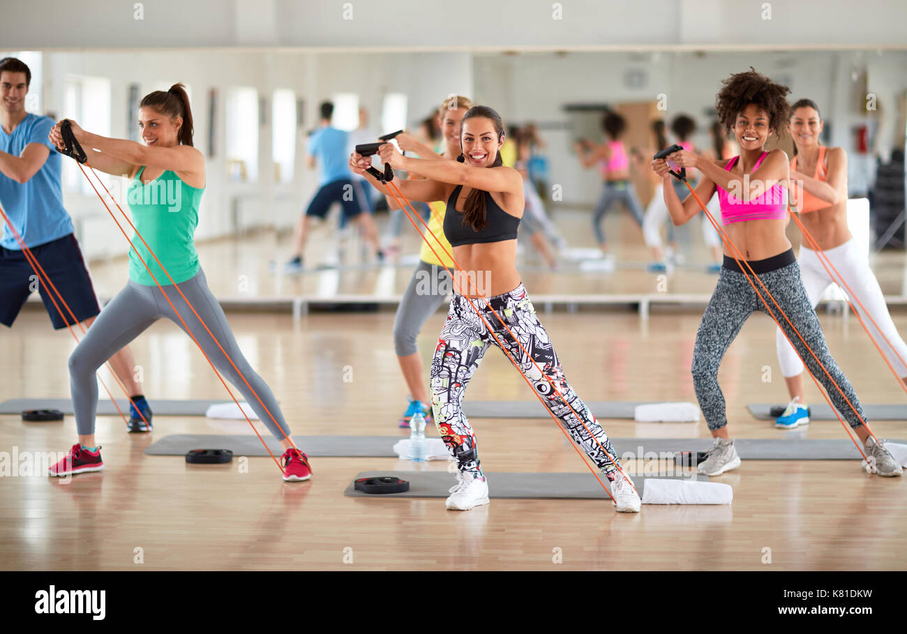 Young group of exercisers doing exercises with resistant rubber in fitness class Stock Photo