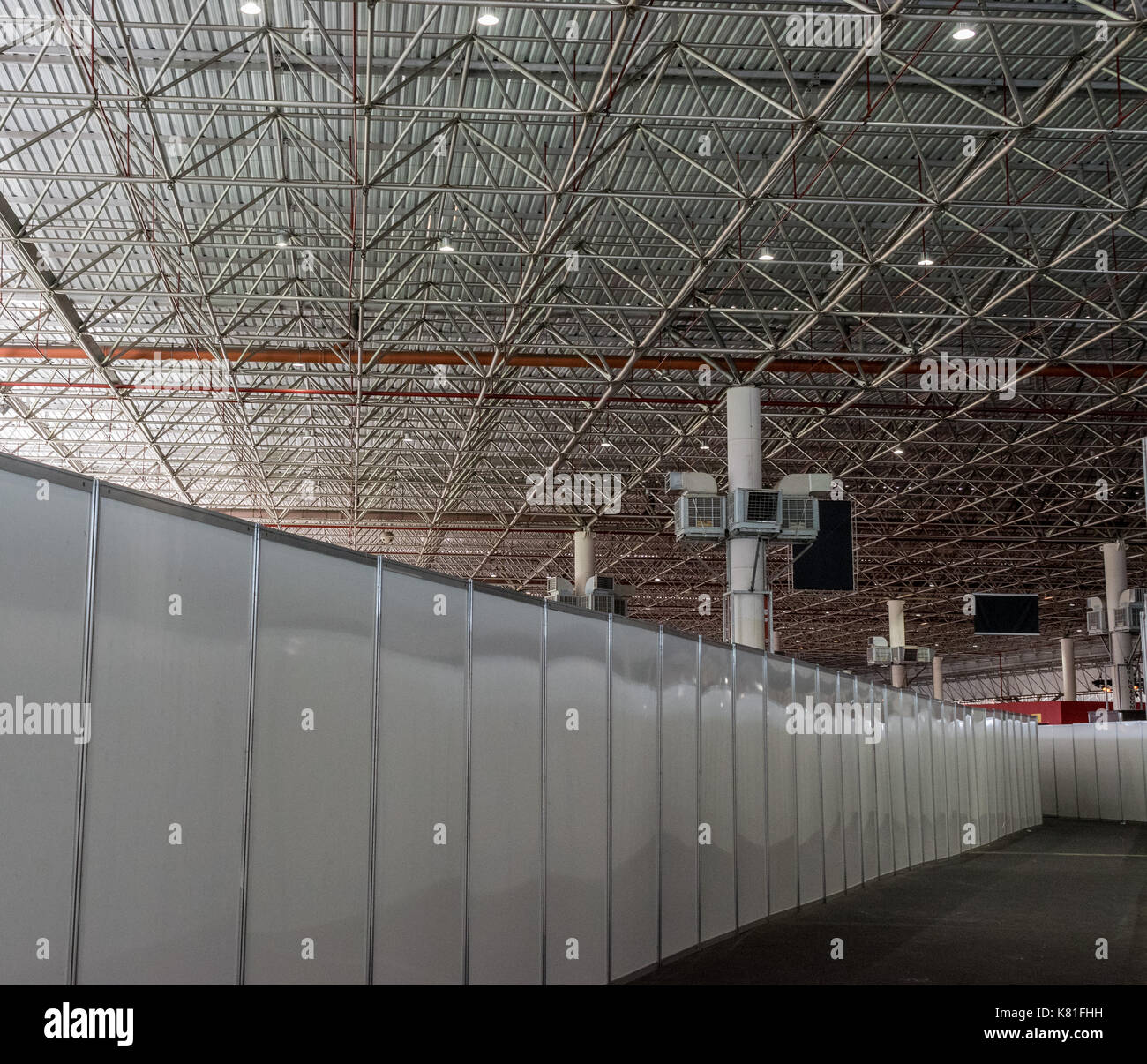 Shed / Hangar interior, with steel beams and support and overhead light, dry wall path and air conditioning units in the background Stock Photo
