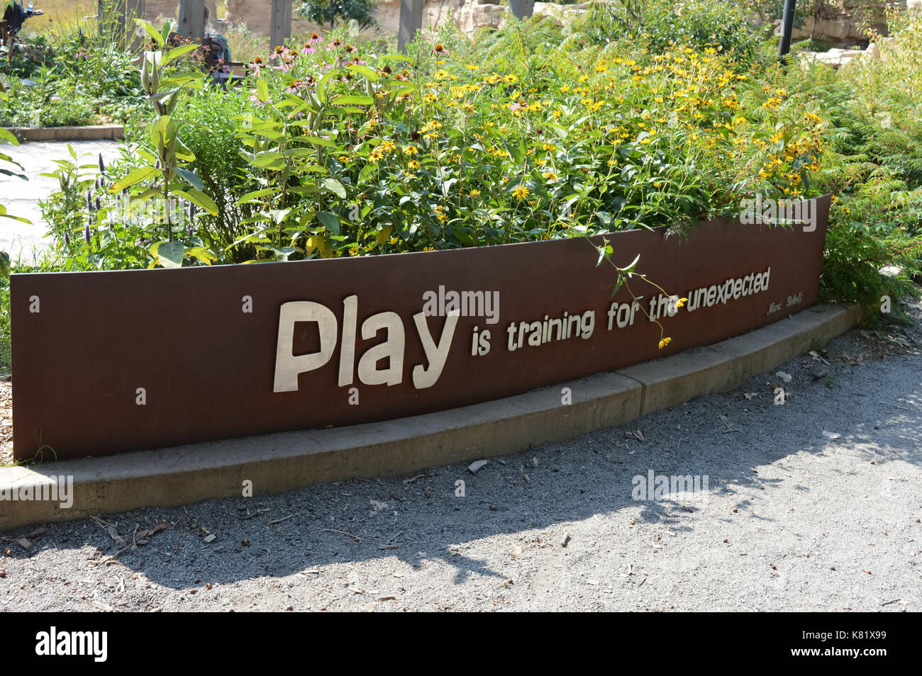 'Play is training for the unexpected' sign in the garden Stock Photo