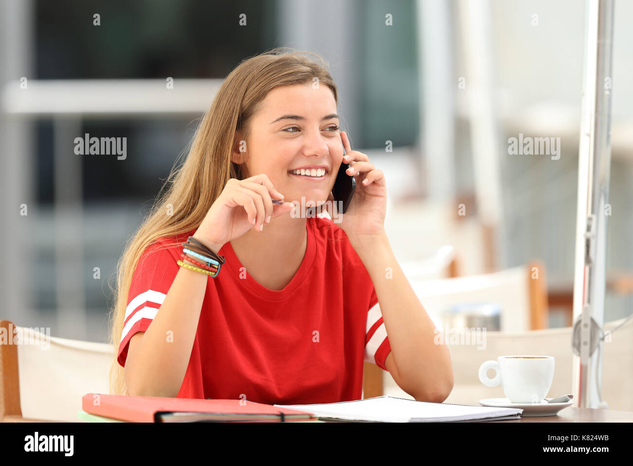 Candid student girl laughing talking on phone siting in a bar terrace Stock Photo