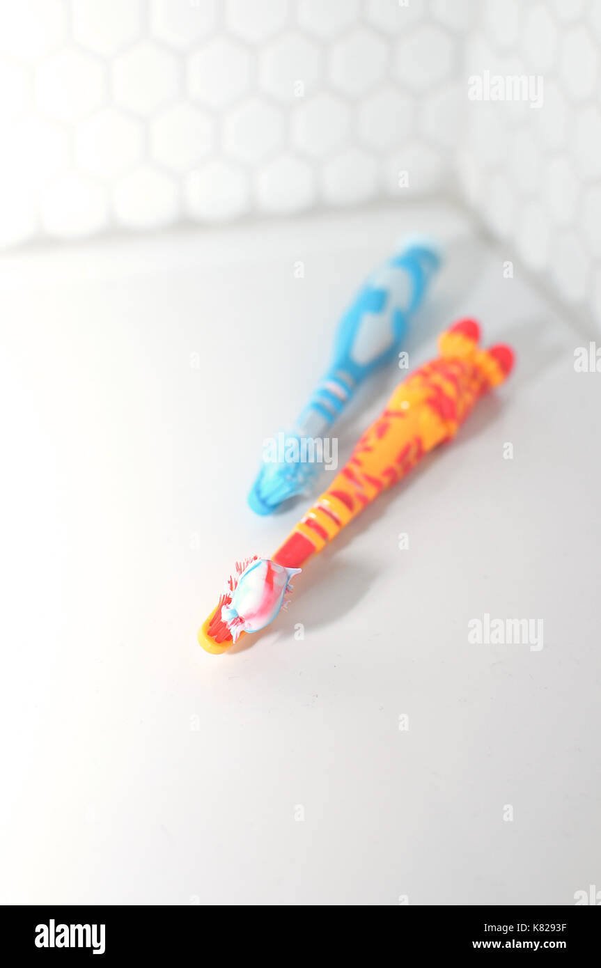 Toothpaste and toothbrushes on a sink in a bathroom Stock Photo
