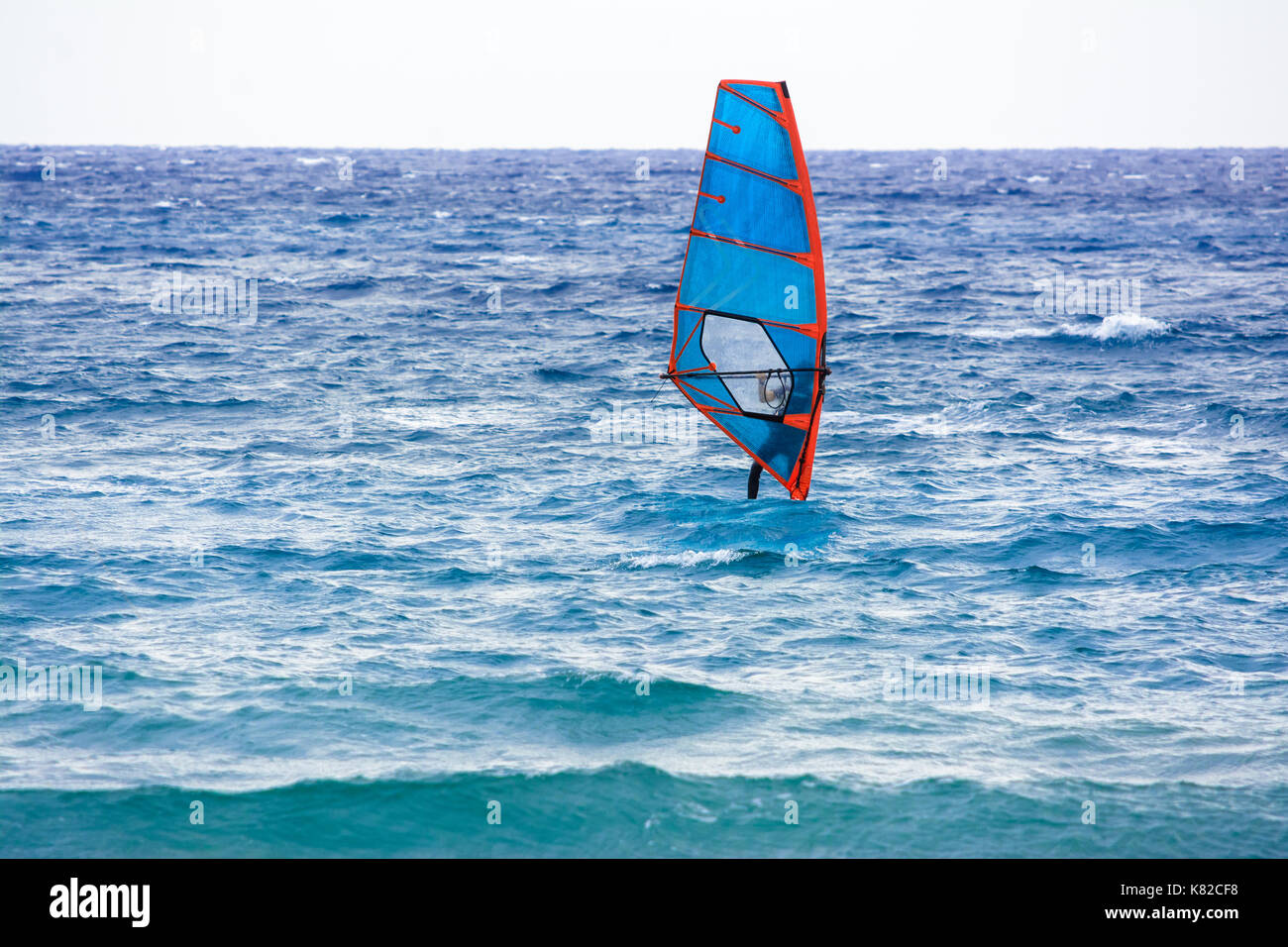 windsurfer that drives its windsurfing speed through the sparkling waves of the Ligurian Sea, in Mediterranean Sea Stock Photo