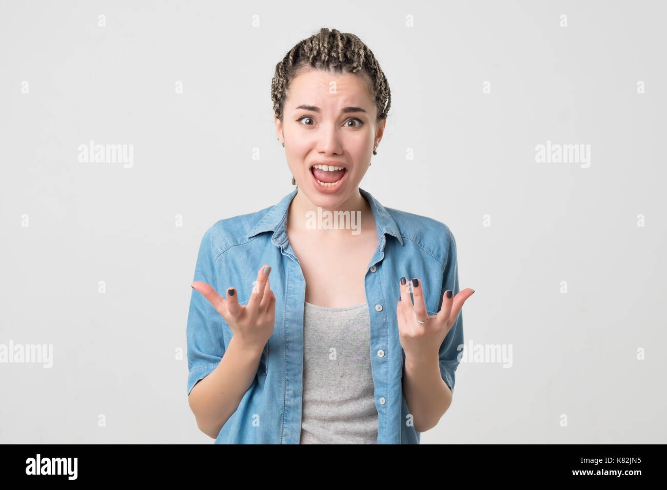Close up isolated portrait of young caucasian annoyed angry woman holding hands in furious gesture. Stock Photo