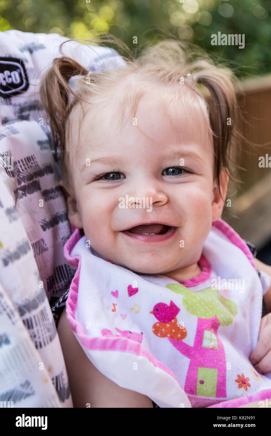 Happy nine month old girl as she eats soft apple chunks outside Stock Photo