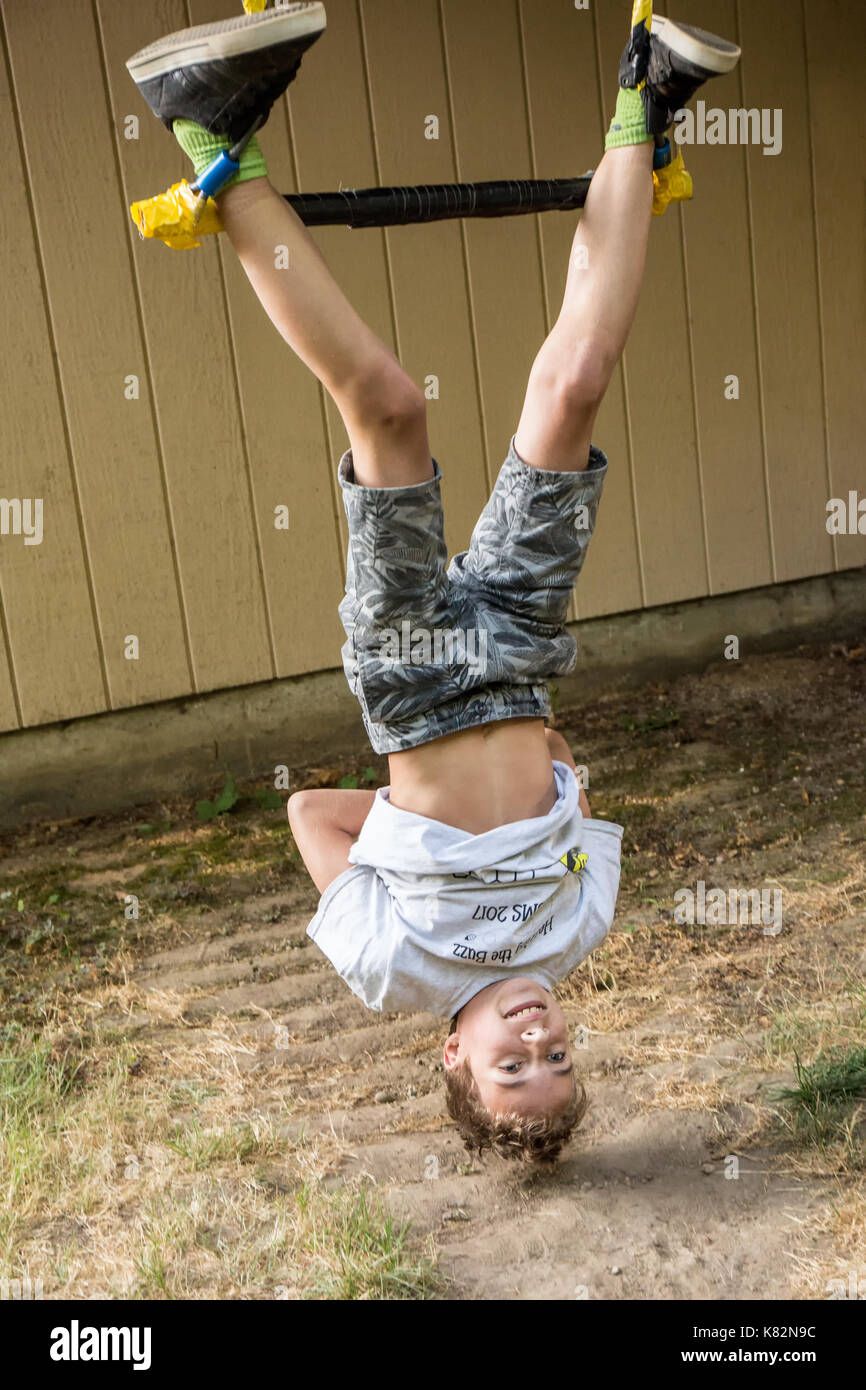 Fourteen year old boy demonstrating his prowess on the trapeze bar in his backyard Stock Photo