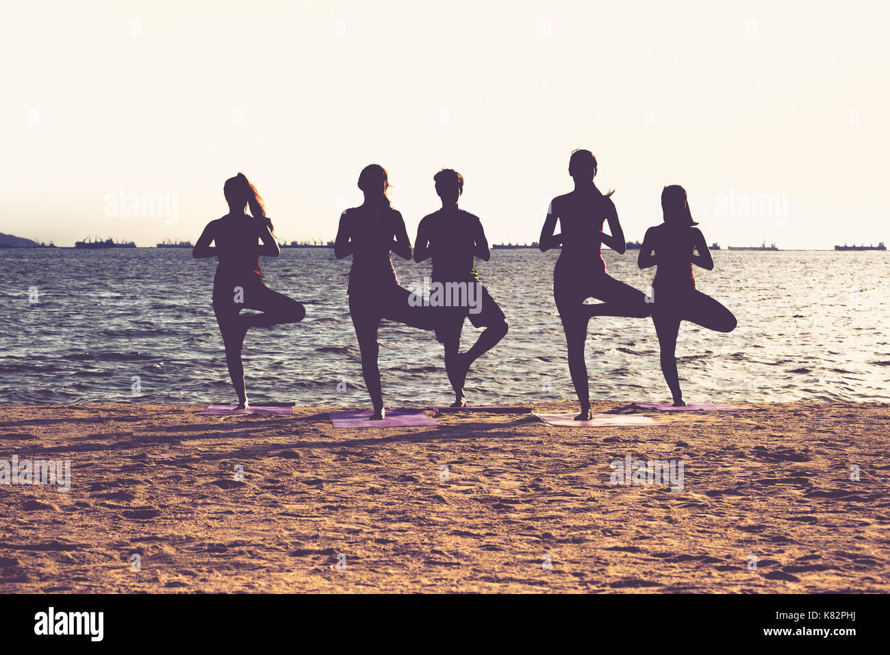 Silhouette of  yoga group of people doing tree pose and namaste with calm relax emotion at beach,Meditation pose,Wellness and Healthy Lifestyle Stock Photo