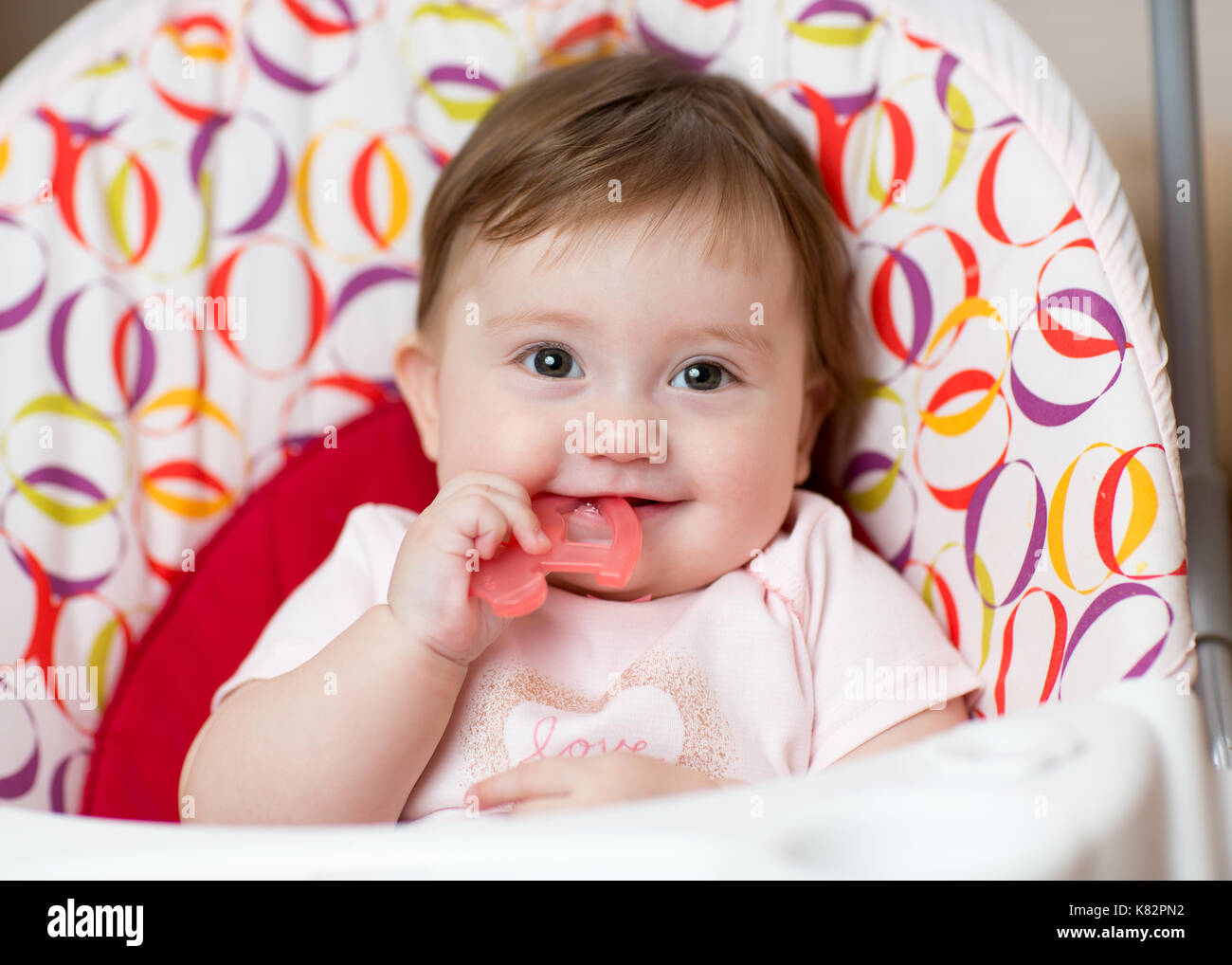 Cute baby chewing on teething toy. First teeth. Stock Photo