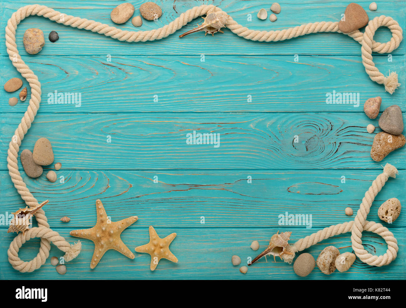 Border with rope, stones, sea shells and starfish on a turquoise wooden ...
