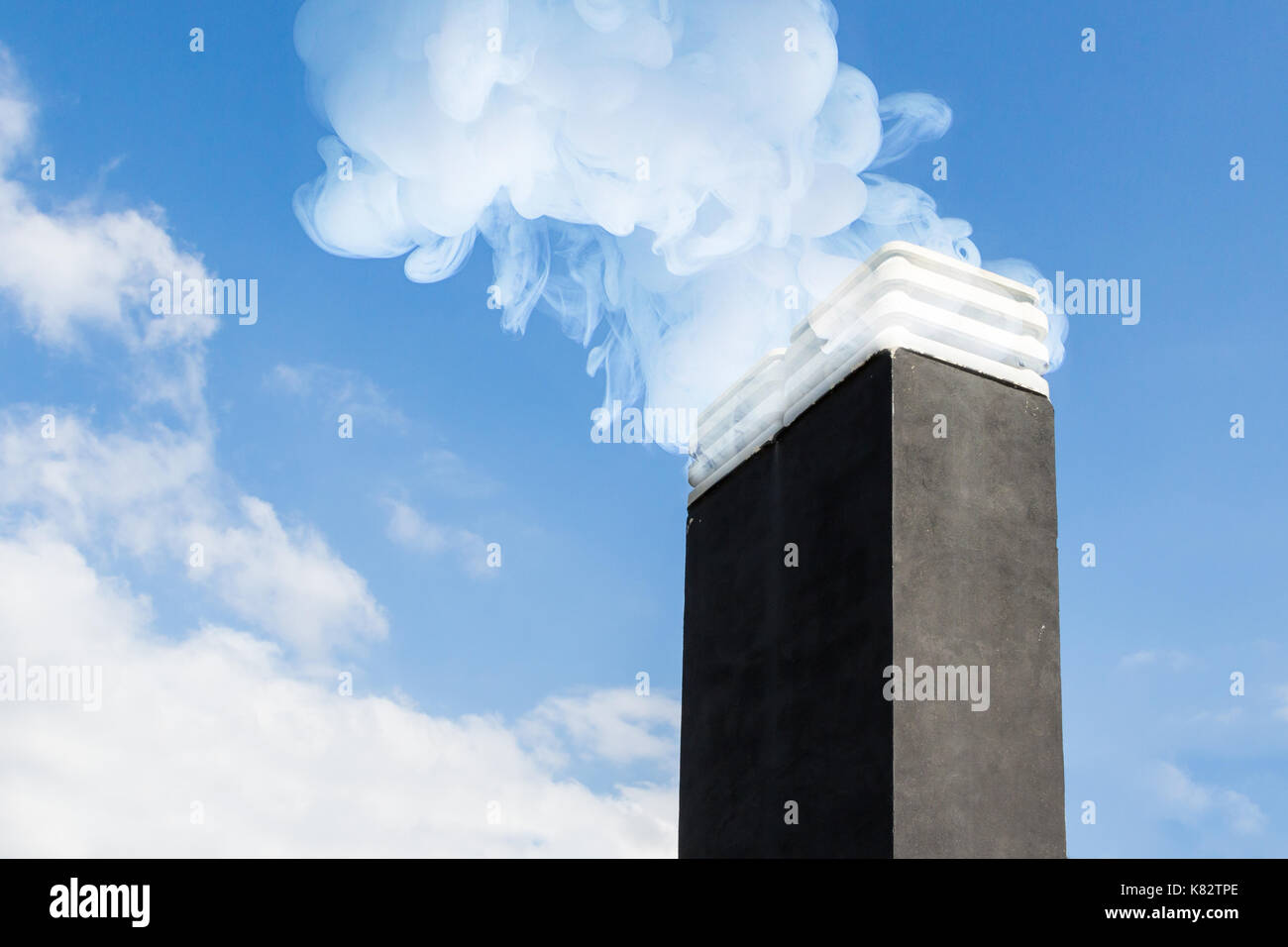 Smoke raising from a chimney in winter day against blue sky Stock Photo