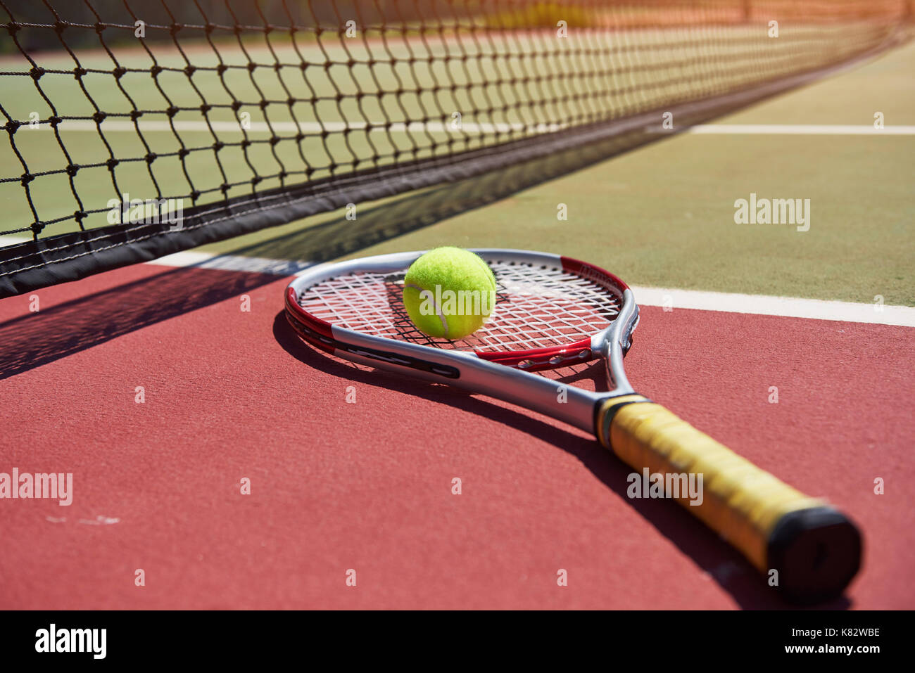 A tennis racket and new tennis ball on a freshly painted tennis court. Stock Photo