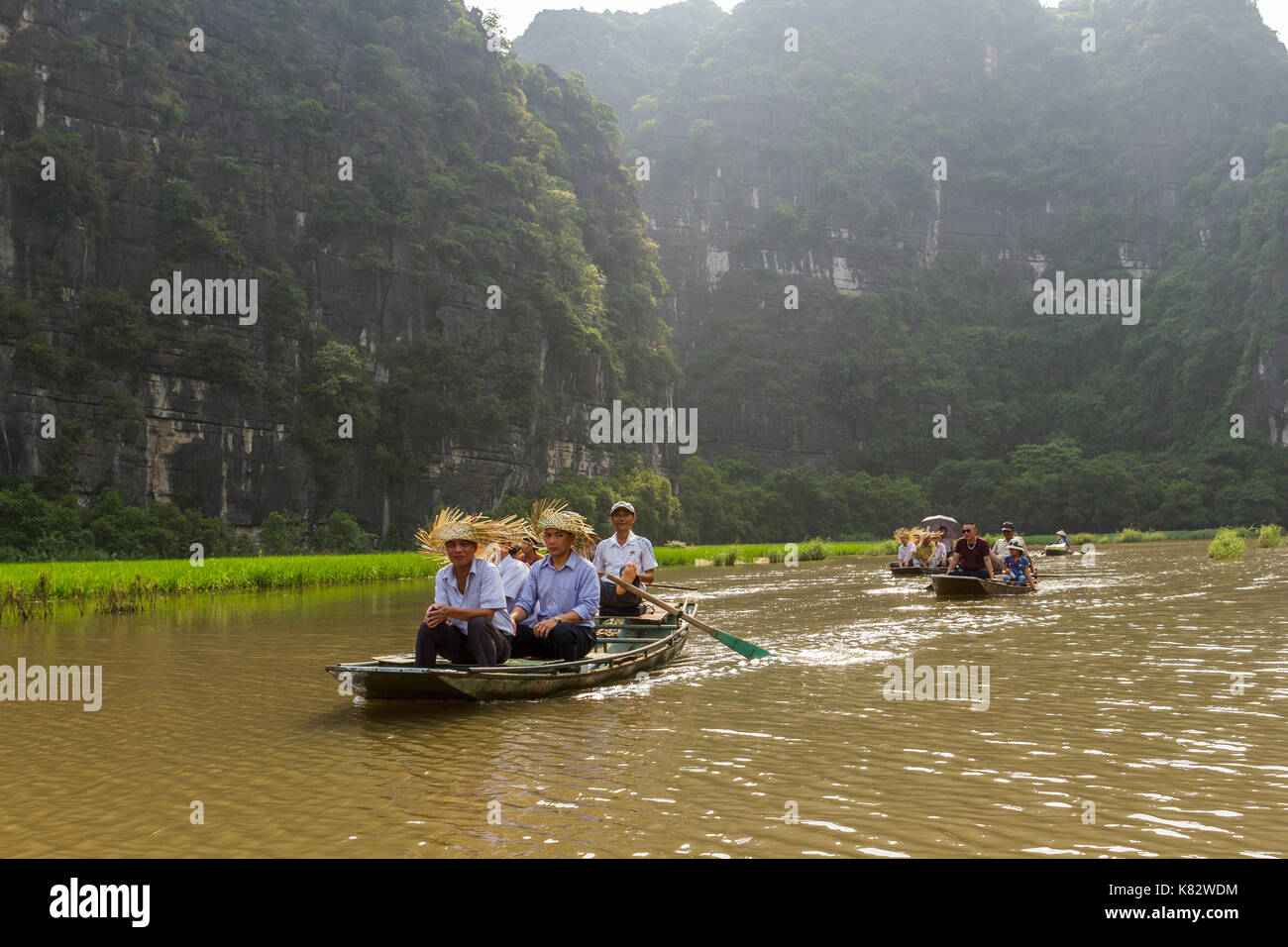 NINH BINH, VIETNAM - 5/6/2016: Boats of tourists on the Ngo Dong River, near Tam Coc village, at the Trang An UNESCO World Heritage site in Ninh Binh, Stock Photo