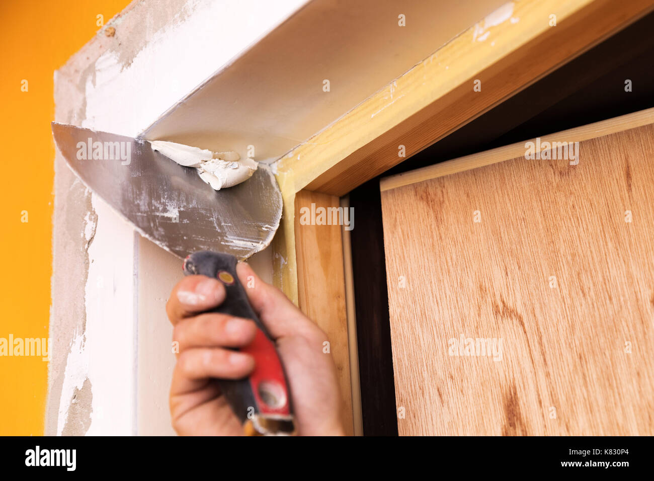 patching plaster around a new door reveals with spatula Stock Photo
