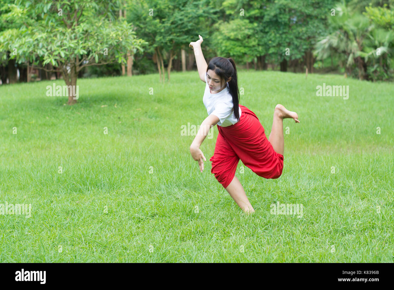 Asian young girl learning Thai dance. Classical Dance in white shirt red loincloth, Demonstrate dance in the garden Stock Photo