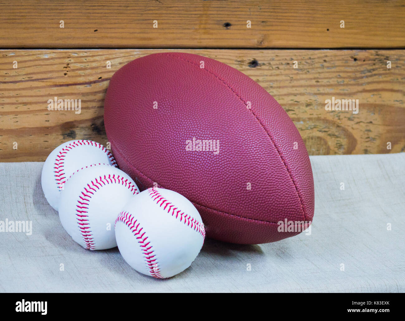 football and 3 baseballs against a wooden wall Stock Photo Alamy