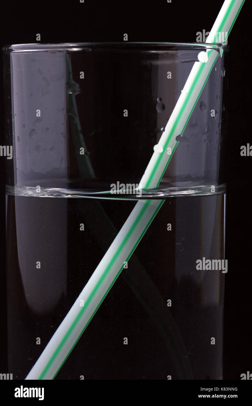 Detail eines Trinkhalmes mit schwarzen hintergrund im Wasserglas Stock Photo