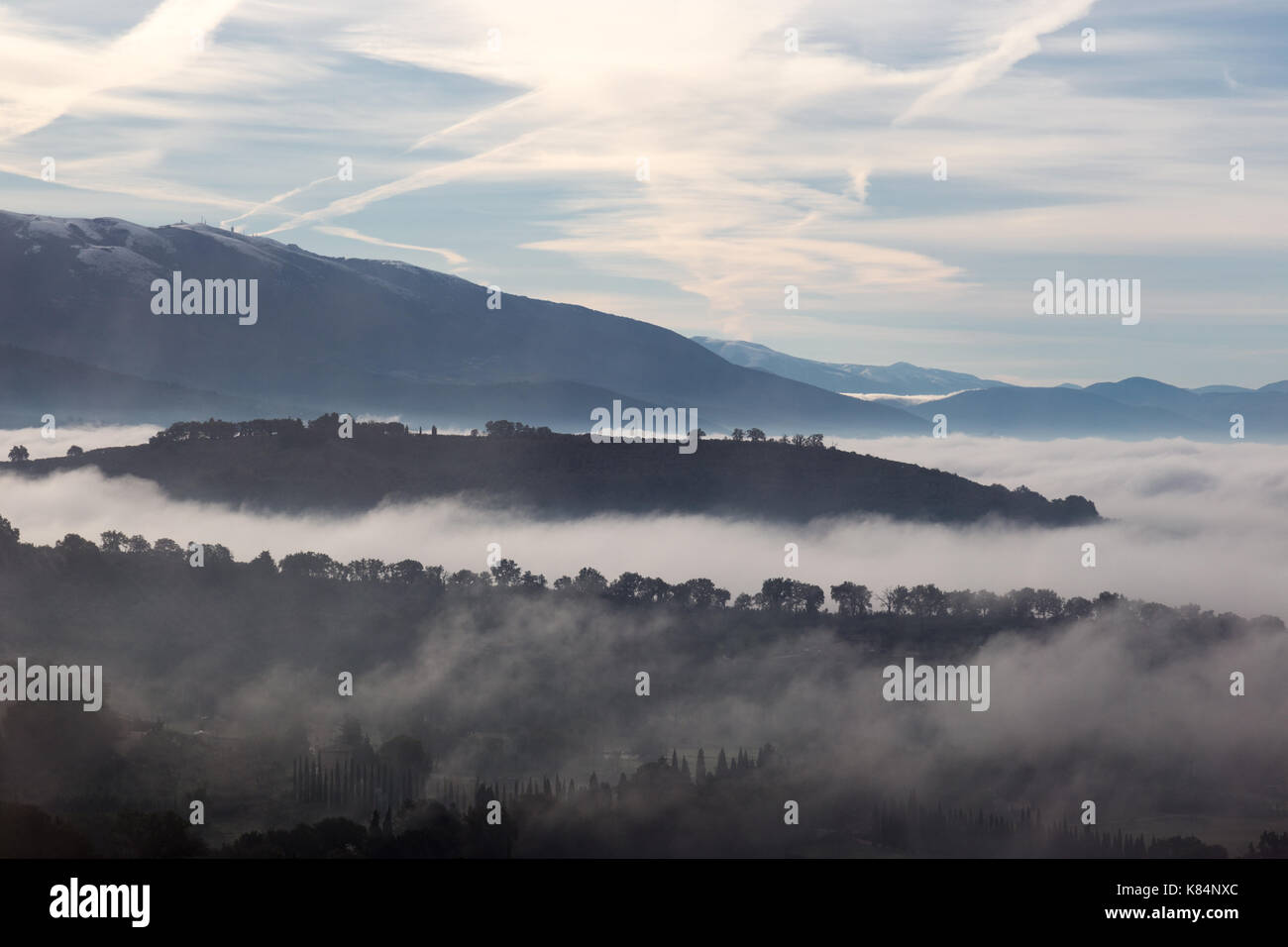 Valley filled by fog with hills and tree emerging from the mist Stock Photo