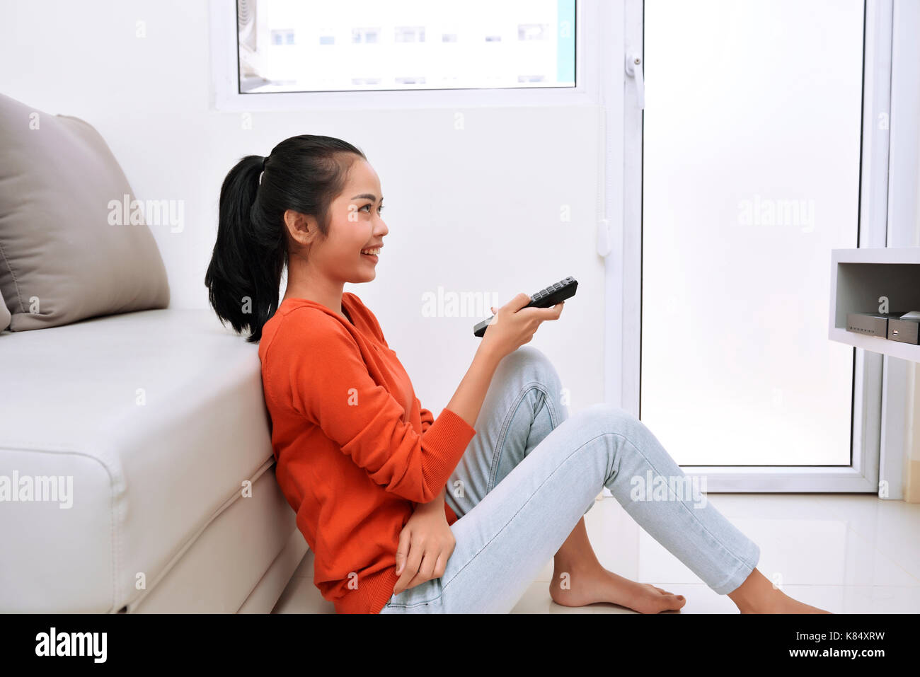 Young asian woman watching television while sitting on the floor Stock Photo