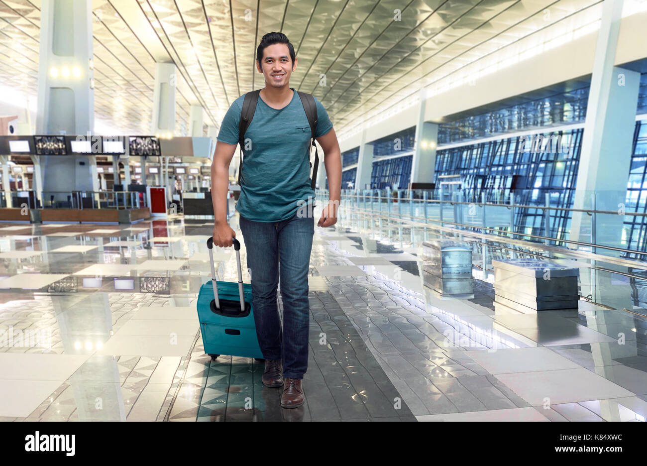 Handsome asian traveler walking with bag and suitcase on the airport Stock Photo
