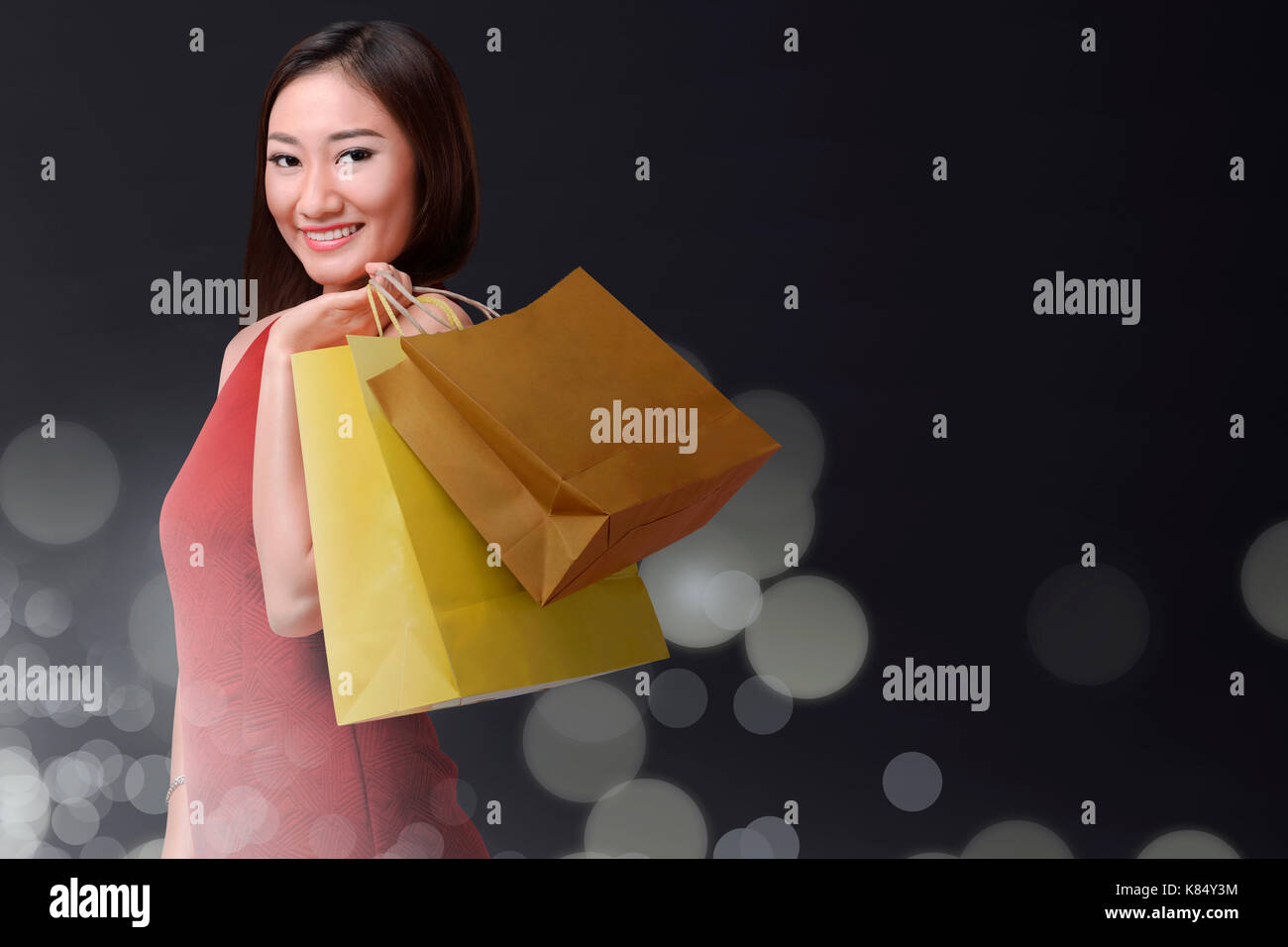 Smiling asian woman with bag shopping in black friday holiday over bokeh background Stock Photo