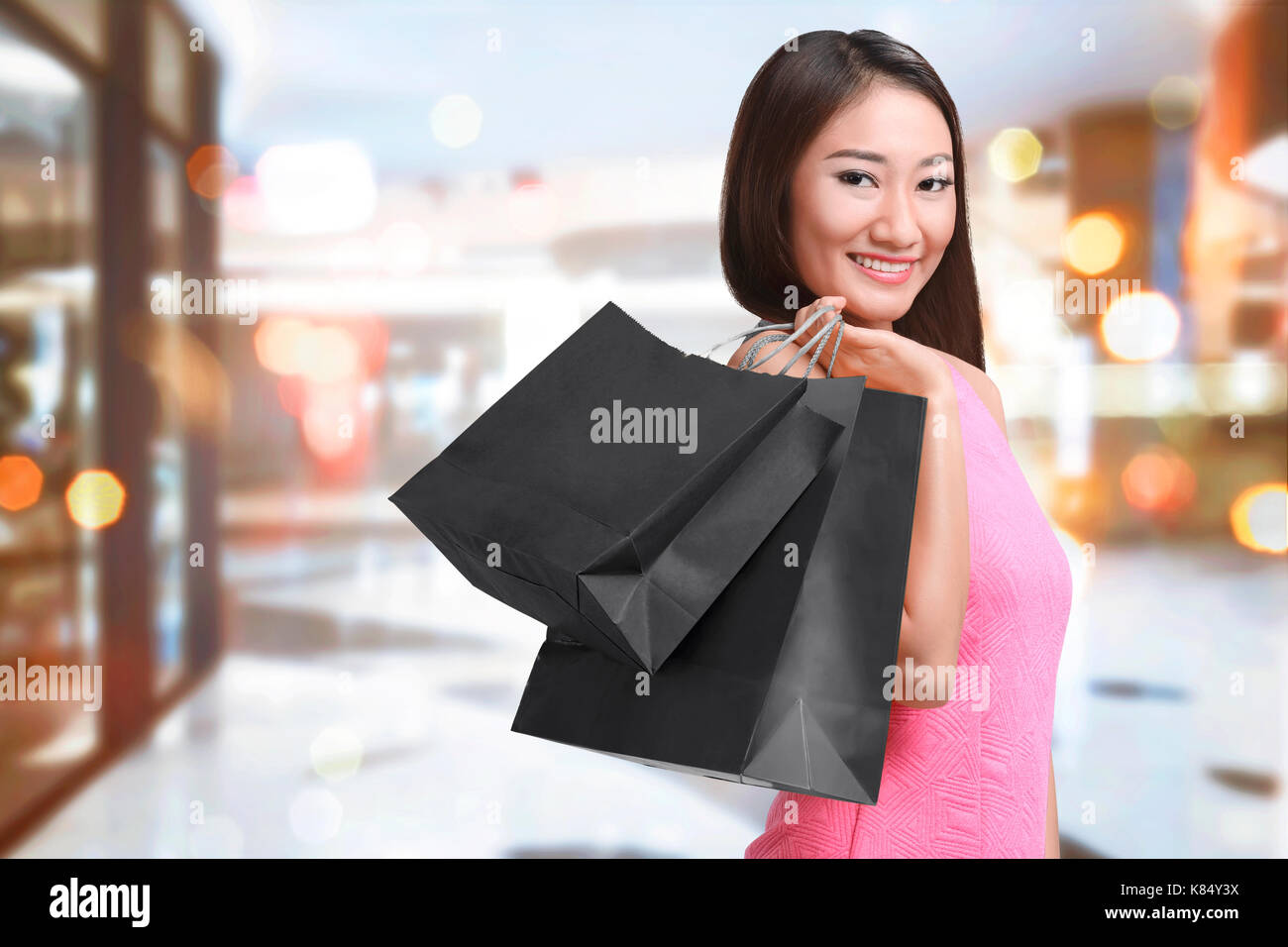 Smiling asian woman with bag shopping in black friday holiday on the mall Stock Photo