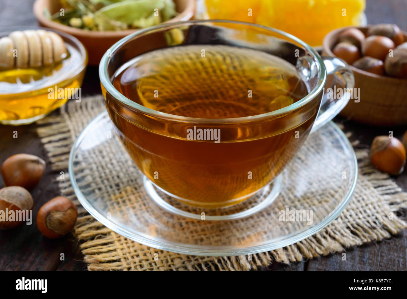 A cup of fresh fragrant herbal tea with honey and hazelnuts on a dark wooden background. Close-up. Stock Photo