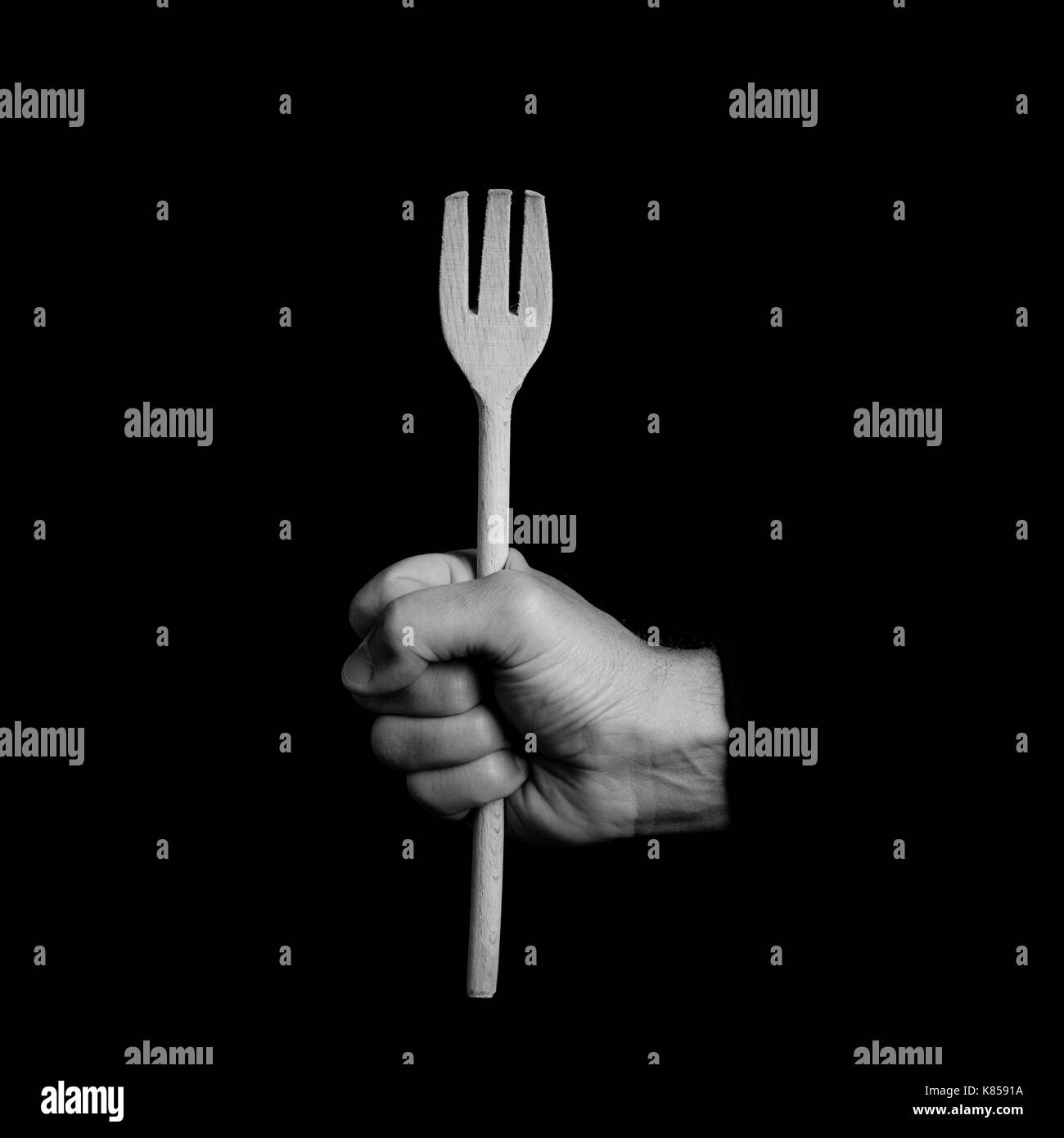 wooden fork - kitchen tools in a man's hand - black and white photo Stock Photo