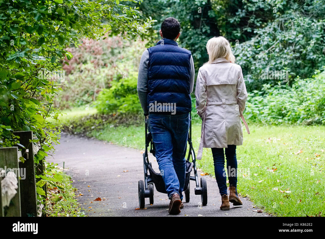 Summers Road, Godalming. 18th September 2017. UK Weather. Cloud cover began to clear this morning over the Home Counties, although the northerly wind meant a distinctly Autumnal feel to the weather. A couple walking their child around Broadwater Lake in Godalming, Surrey. Credit: james jagger/Alamy Live News Stock Photo