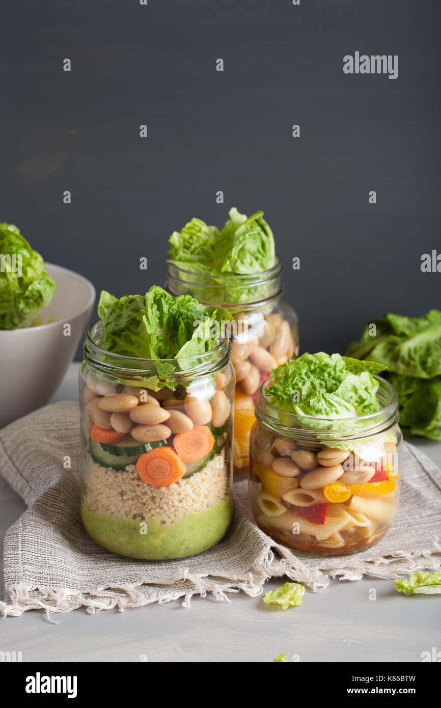 vegan couscous and pasta salad in mason jars with vegetables beans