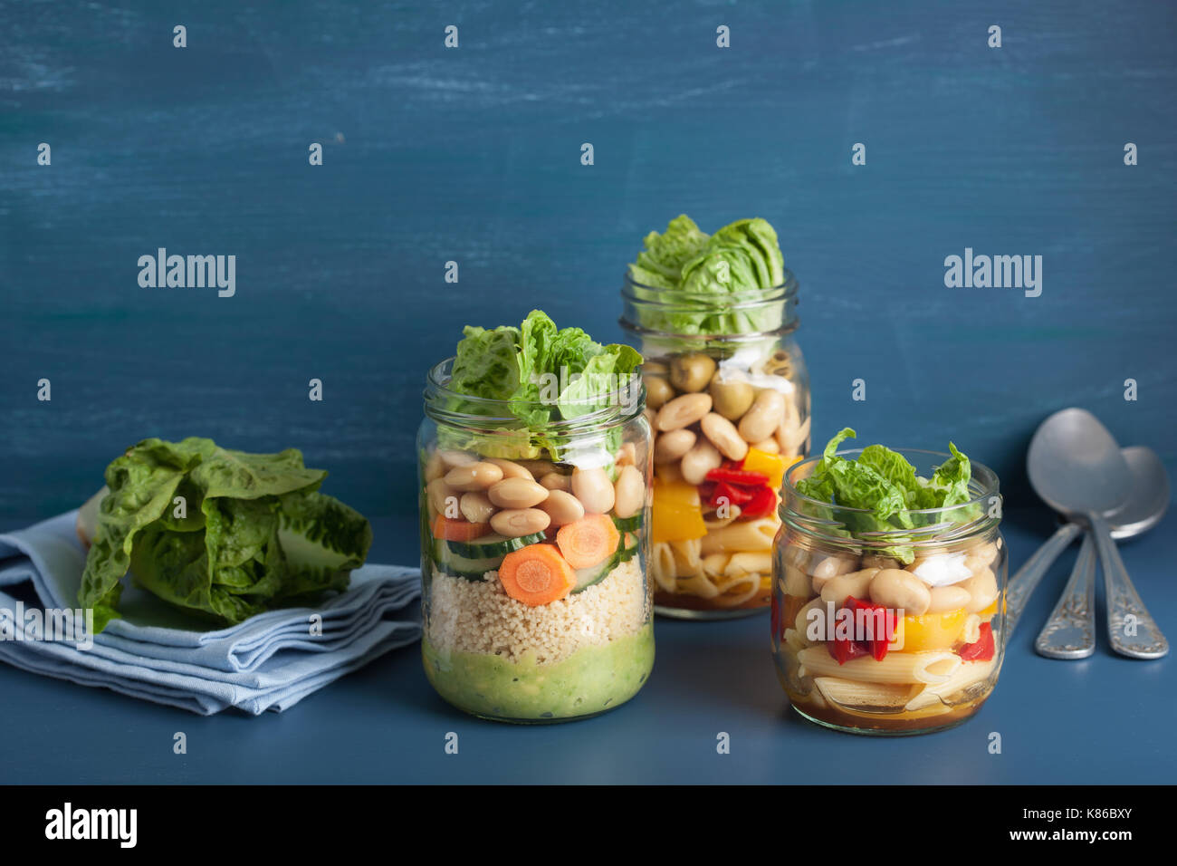 vegan couscous and pasta salad in mason jars with vegetables beans