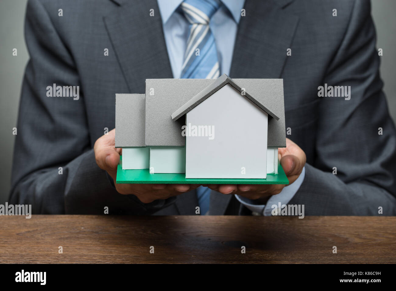 Close-up Of Businessman Holding House Model At Wooden Desk Stock Photo ...