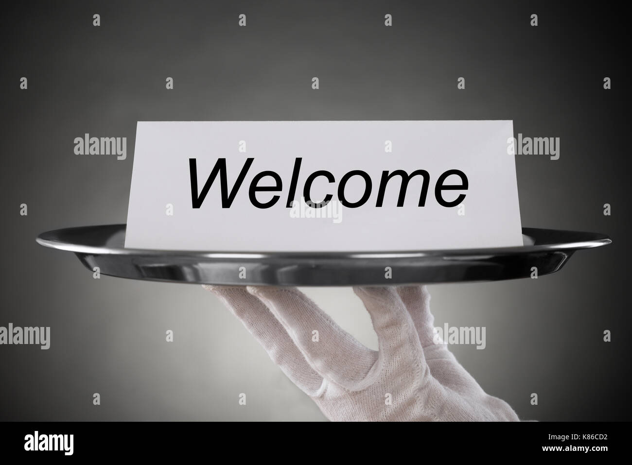 Close-up Of Waiter Holding Plate With Welcome Text On Paper Stock Photo